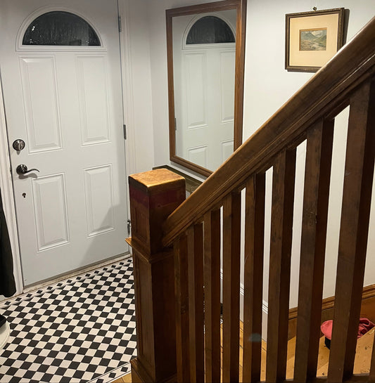 Foyer with a staircase, white door, and checkered floor.